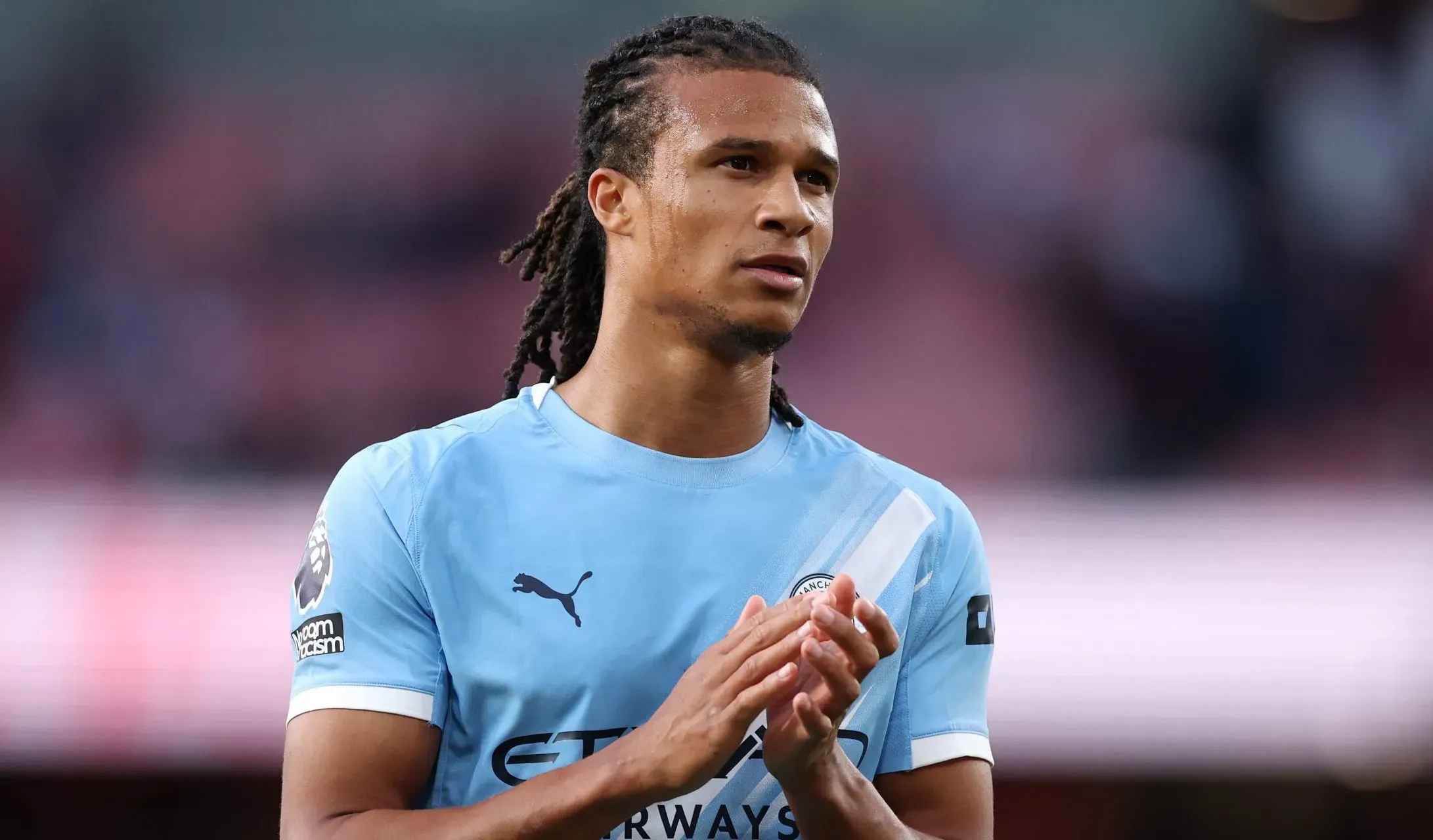 Nathan Aké, em campo, aplaudindo a equipe e torcida do Manchester City