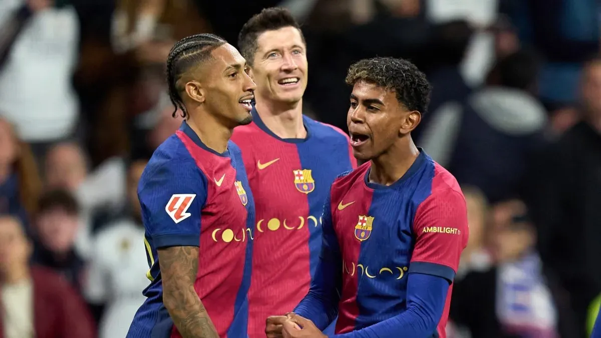 Raphinha of FC Barcelona celebrates scoring his team's fourth goal with teammates Robert Lewandowski and Lamine Yamal during the LaLiga match between Real Madrid CF and FC Barcelona at Estadio Santiago Bernabeu on October 26, 2024 in Madrid, Spain.