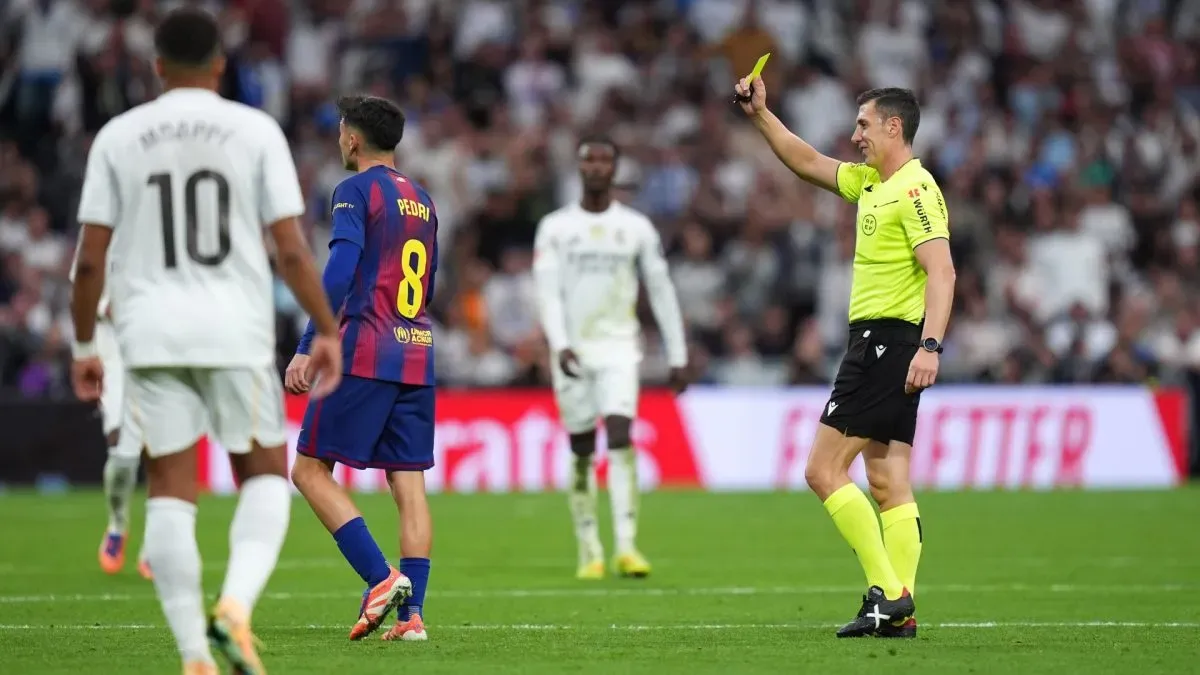 Referee Cesar Soto Grado shows a yellow card to Pedri of FC Barcelona.