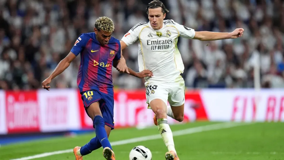 Lamine Yamal of FC Barcelona passes the ball whilst under pressure from Alvaro Carreras of Real Madrid.