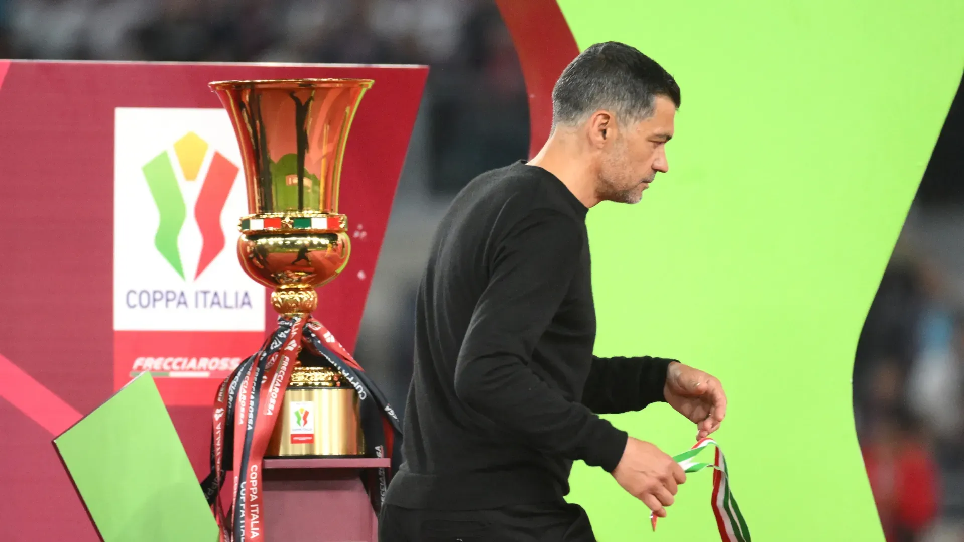 Sergio Conceicao, Head Coach of AC Milan, walks past the Coppa Italia trophy.
